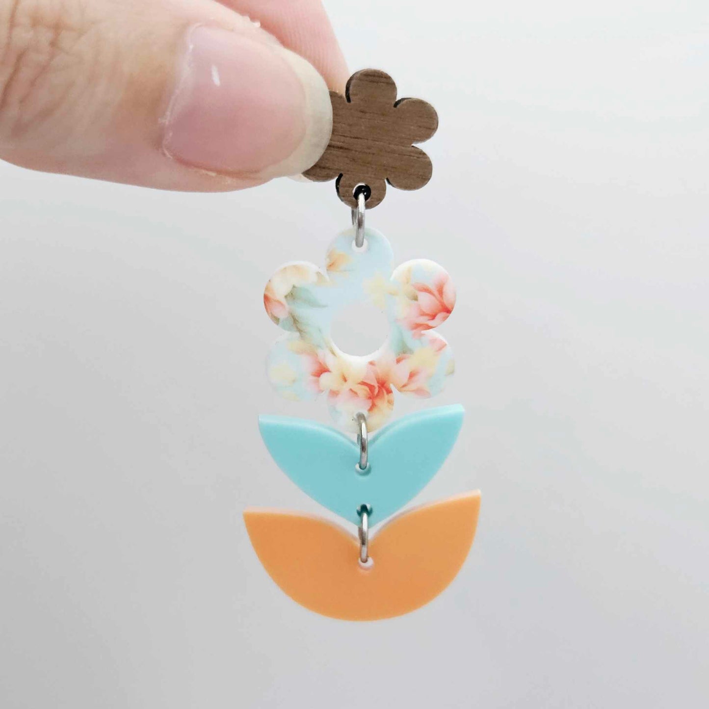 Assembled three-piece acrylic floral dangle hanging from a 14mm walnut flower topper, Floral Bloom UV printed flower with aqua and orange layered leaf pieces