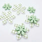 Green gingham UV print and pastel green acrylic two layer flower dangle blanks shown laying flat, with some flowers stacked to show layered effect and others positioned side by side