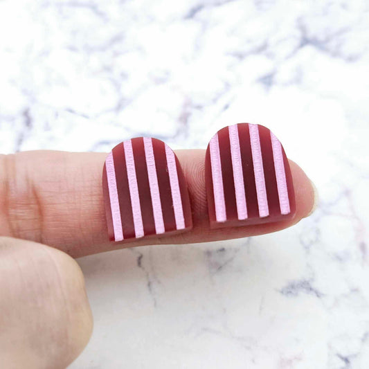 16mm port wine striped arch acrylic stud blanks paint filled with light pink, shown on a finger for size reference and finished look