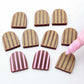 16mm port wine striped acrylic arch stud blanks showing paint filled example and unpainted pieces with protective film, pictured with a light pink Posca paint pen