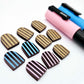 Chocolate brown striped arch stud blanks with engraved stripes, one pair paint filled light pink, one pair painted filled light blue, with additional unpainted pieces shown with protective film on