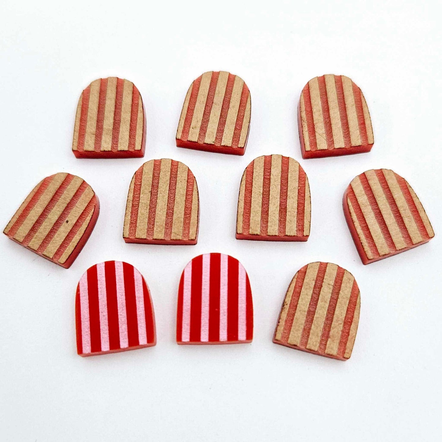 Red striped arch stud blanks with engraved stripes, one pair paint filled light pink and peeled, with additional unpainted pieces shown with protective film on