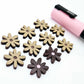 Chocolate brown acrylic flower stud blanks showing paint filled light pink example and unpainted pieces with protective film, pictured with a light pink Posca paint pen