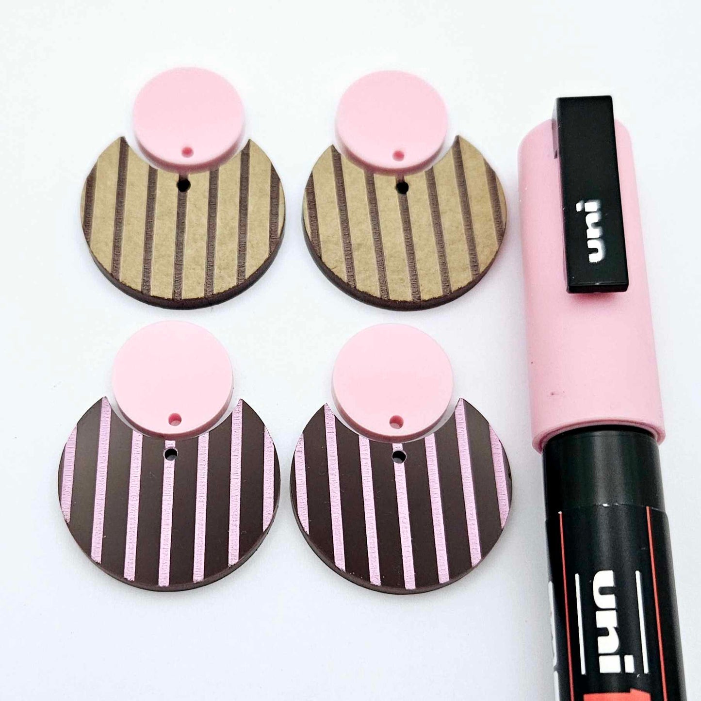 Nested circle dangle blanks showing one piece paint filled light pink and peeled, with another pair unpainted and with protective film on, pictured with a pink Posca paint pen