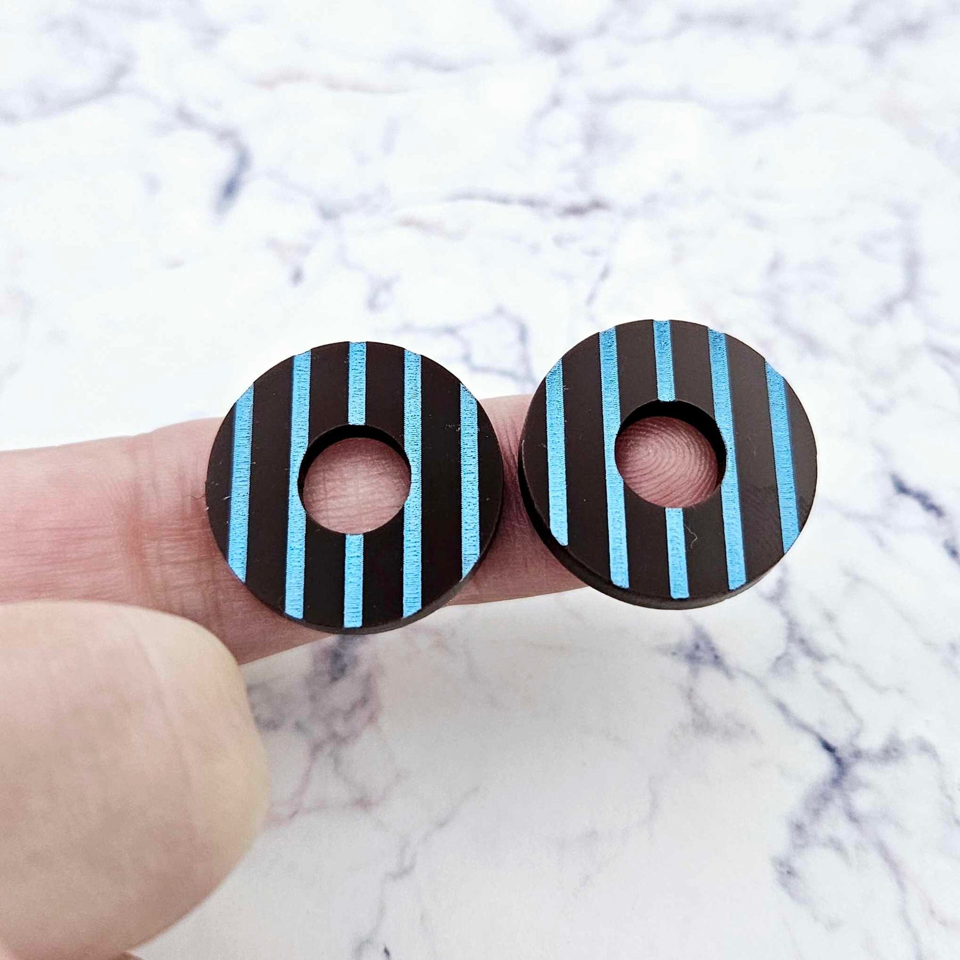 22mm chocolate brown striped hoop acrylic stud blanks paint filled with light blue, shown on a finger for size reference and finished look