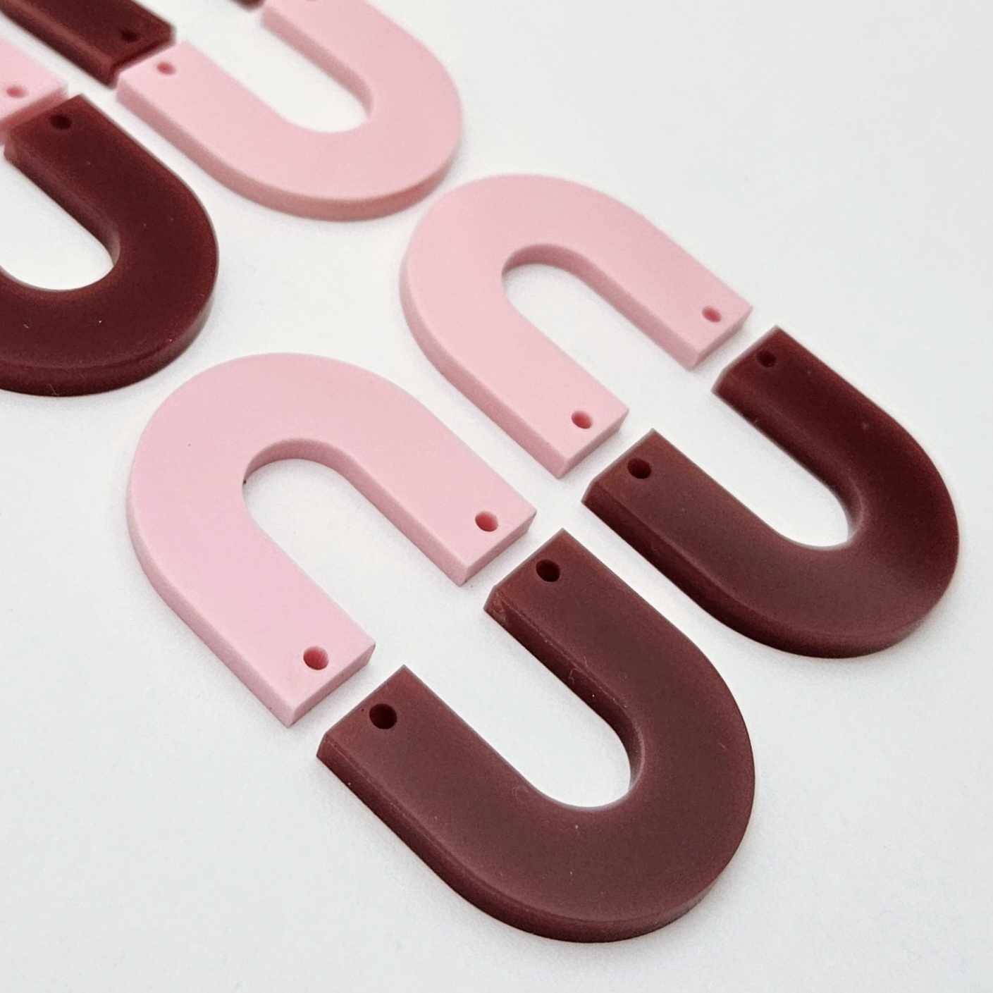 Layered U dangle blanks in pastel pink and port wine (burgundy) acrylic, two pairs shown unassembled laying flat with matching U-shaped pieces