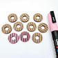 22mm port wine (burgundy) striped acrylic hoop stud blanks showing paint filled example and unpainted pieces with protective film, pictured with a light pink Posca paint pen