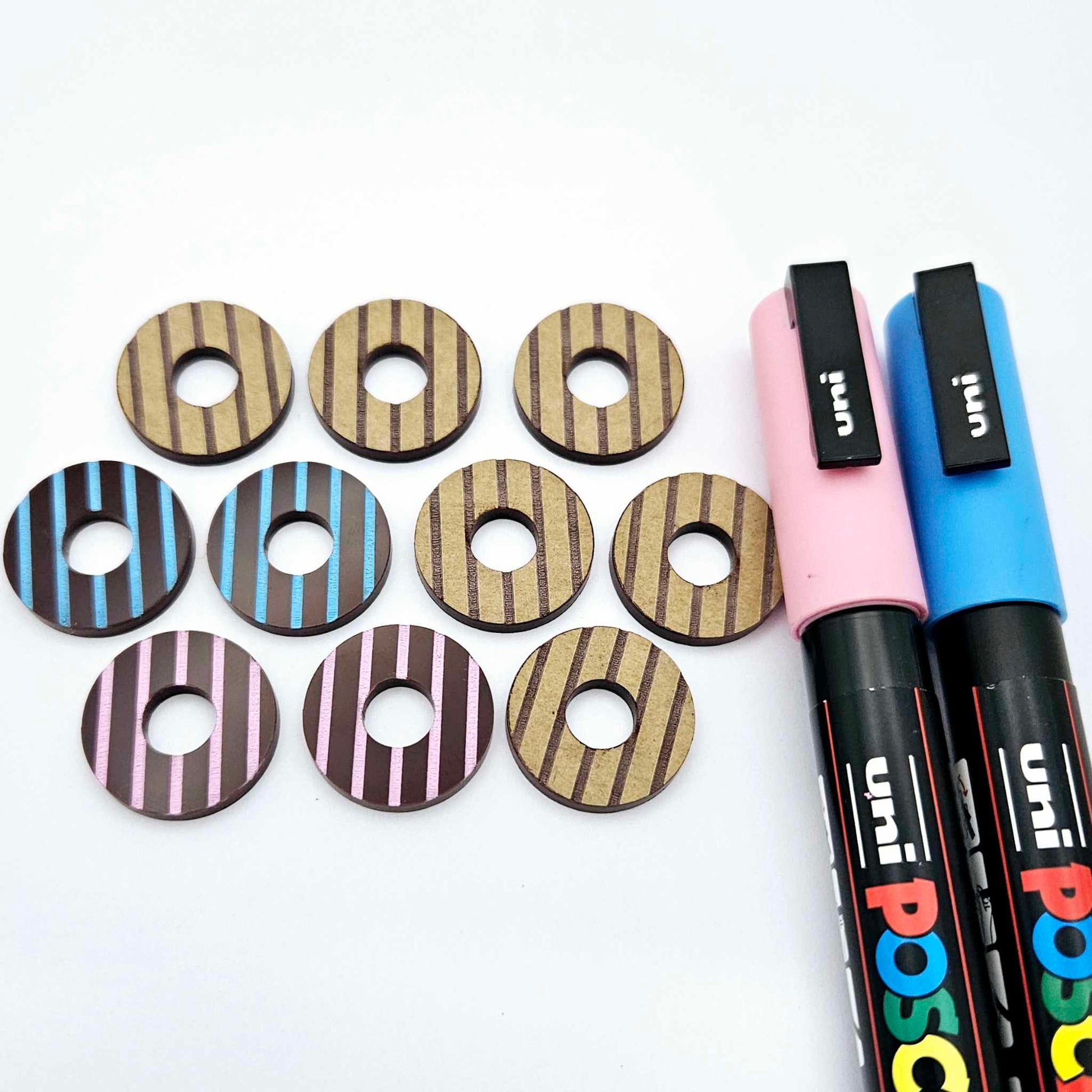 22mm chocolate brown striped acrylic hoop stud blanks showing paint filled examples and unpainted pieces with protective film, pictured with a light pink and light blue Posca paint pen