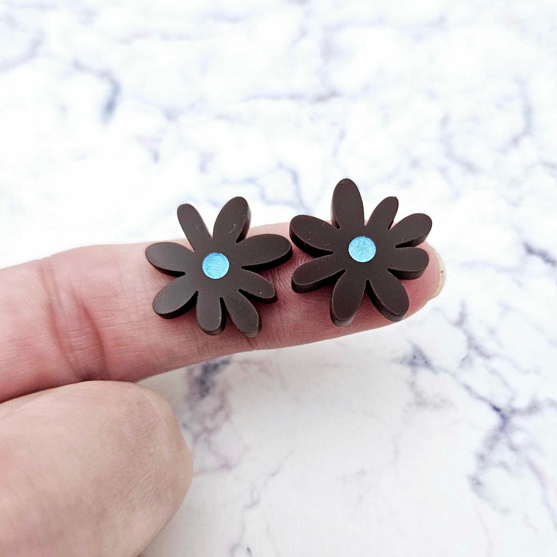 17mm chocolate brown acrylic flower stud blanks with engraved centre detail, one pair paint filled light blue shown on finger for size reference