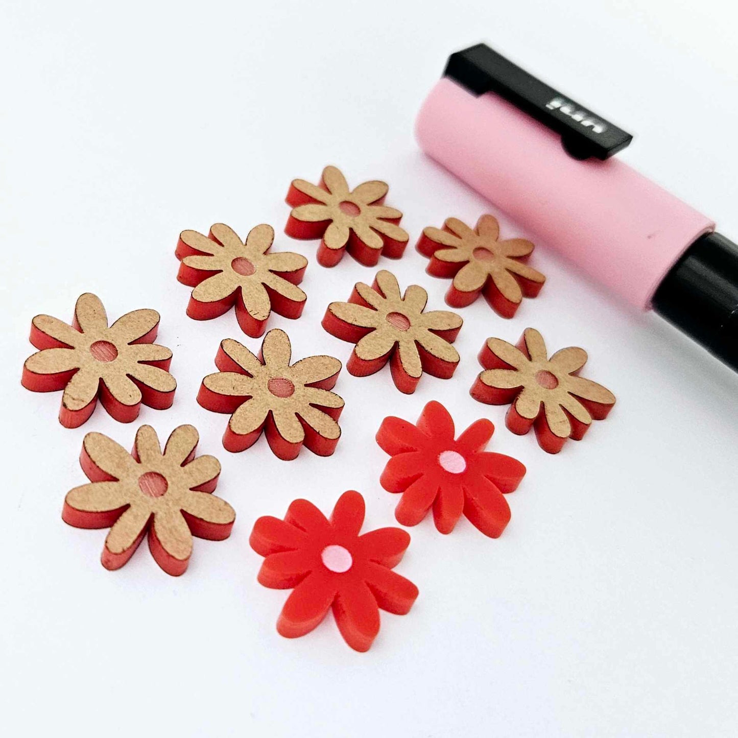 Red acrylic flower stud blanks showing paint filled light pink example and unpainted pieces with protective film, pictured with a light pink Posca paint pen