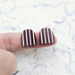 16mm chocolate brown striped arch acrylic stud blanks paint filled with light pink, shown on a finger for size reference and finished look
