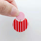 Nested circle acrylic dangle earring with pastel pink topper and red striped base, paint filled light pink and fully assembled to show finished look