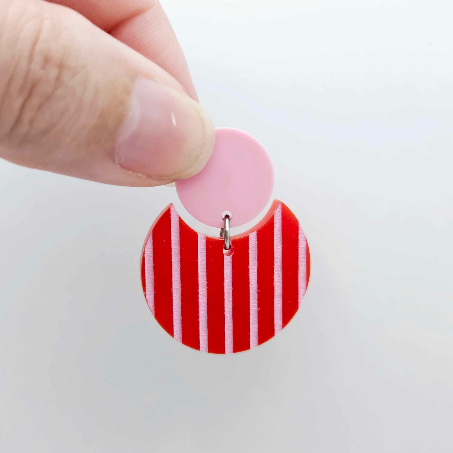 Nested circle acrylic dangle earring with pastel pink topper and red striped base, paint filled light pink and fully assembled to show finished look