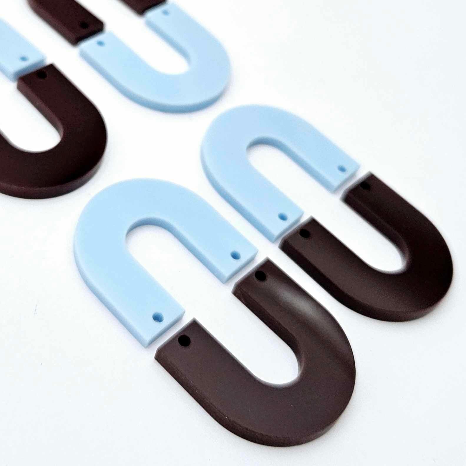 Layered U dangle blanks in pastel blue and chocolate brown acrylic, two pairs shown unassembled laying flat with matching U-shaped pieces