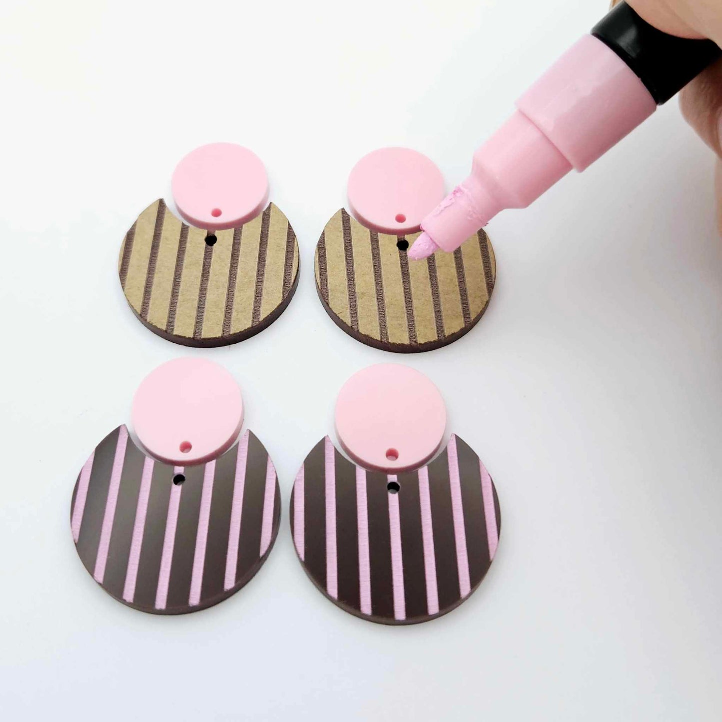 Nested circle dangle blanks showing one piece paint filled light pink and peeled, with another pair unpainted and with protective film on, pictured with a pink Posca paint pen