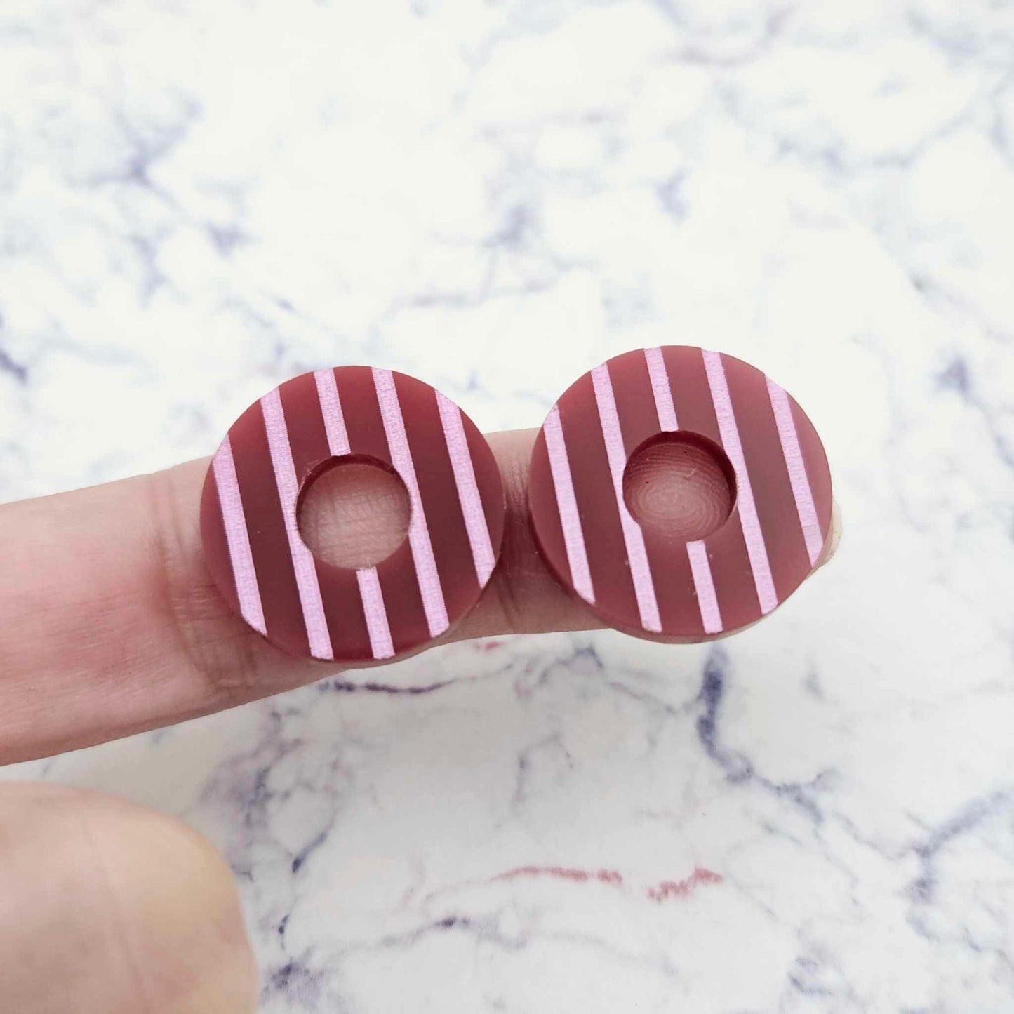 22mm port wine (burgundy) striped hoop acrylic stud blanks paint filled with light pink, shown on a finger for size reference and finished look
