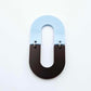 Layered U shape dangle earring in pastel blue and chocolate brown acrylic, assembled into an open oval design hanging as a statement stud dangle