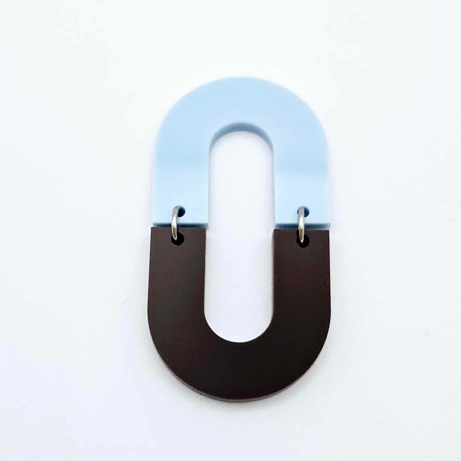 Layered U shape dangle earring in pastel blue and chocolate brown acrylic, assembled into an open oval design hanging as a statement stud dangle