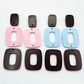 Two pairs of layered rectangle dangle blanks in chocolate brown and pastel pink/blue acrylic, unassembled pieces laid flat showing three-piece design