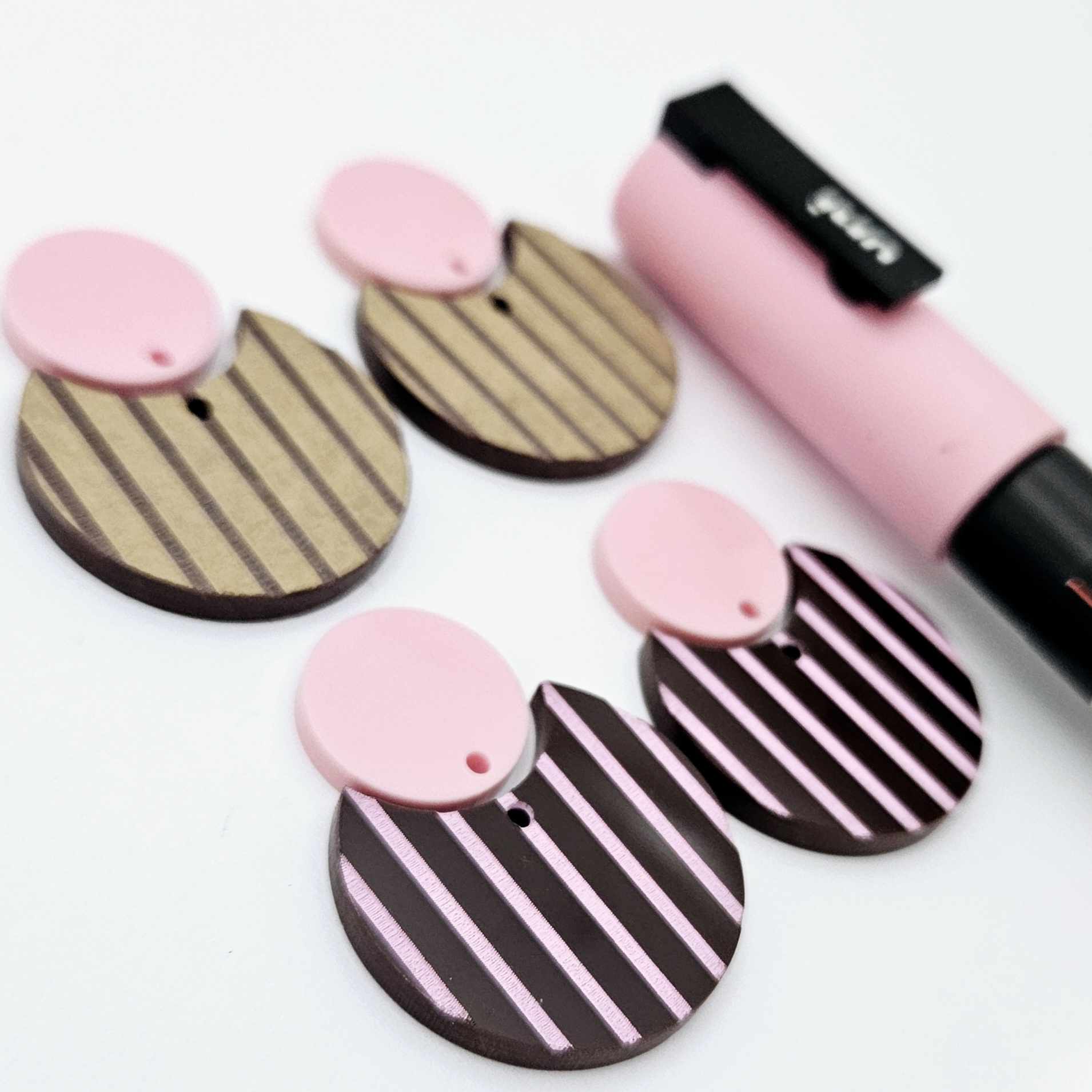 Nested circle dangle blanks showing one piece paint filled light pink and peeled, with another pair unpainted and with protective film on, pictured with a pink Posca paint pen