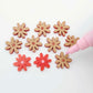 Red acrylic flower stud blanks showing paint filled light pink example and unpainted pieces with protective film, pictured with a light pink Posca paint pen