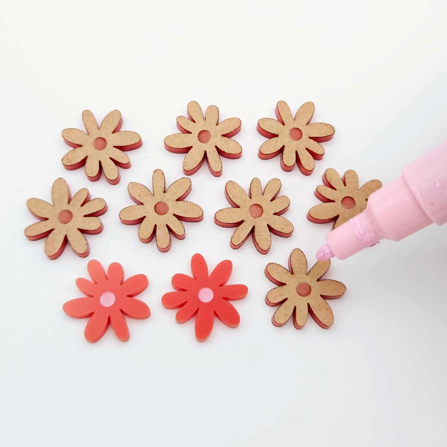 Red acrylic flower stud blanks showing paint filled light pink example and unpainted pieces with protective film, pictured with a light pink Posca paint pen