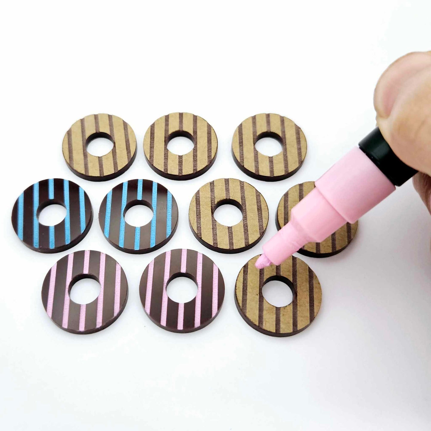 22mm chocolate brown striped acrylic hoop stud blanks showing paint filled examples and unpainted pieces with protective film, pictured with a light pink Posca paint pen
