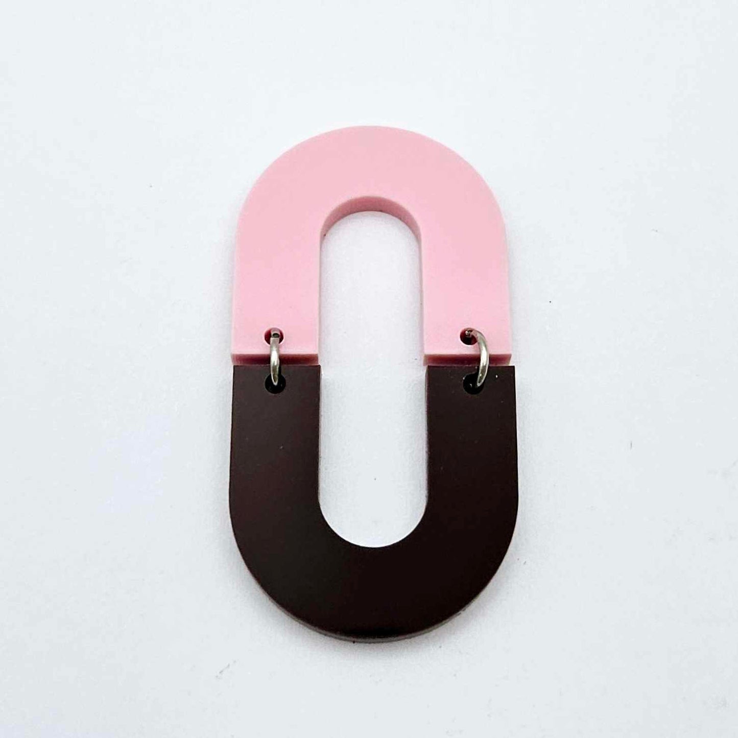 Layered U shape dangle earring in pastel pink and chocolate brown acrylic, assembled into an open oval design hanging as a statement stud dangle