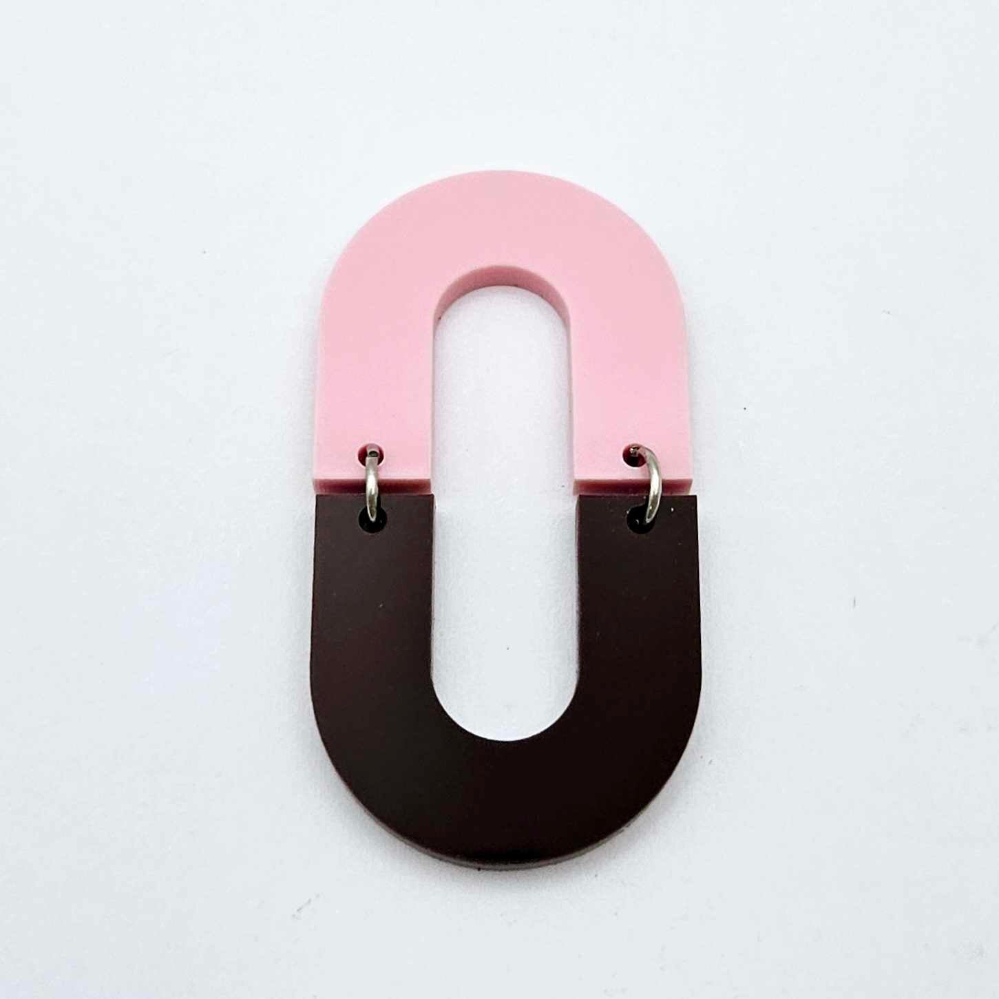 Layered U shape dangle earring in pastel pink and chocolate brown acrylic, assembled into an open oval design hanging as a statement stud dangle