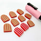 16mm red striped acrylic arch stud blanks showing paint filled example and unpainted pieces with protective film, pictured with a light pink Posca paint pen