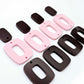 Two pairs of layered rectangle dangle blanks in chocolate brown and pastel pink acrylic, unassembled pieces laid flat showing three-piece design
