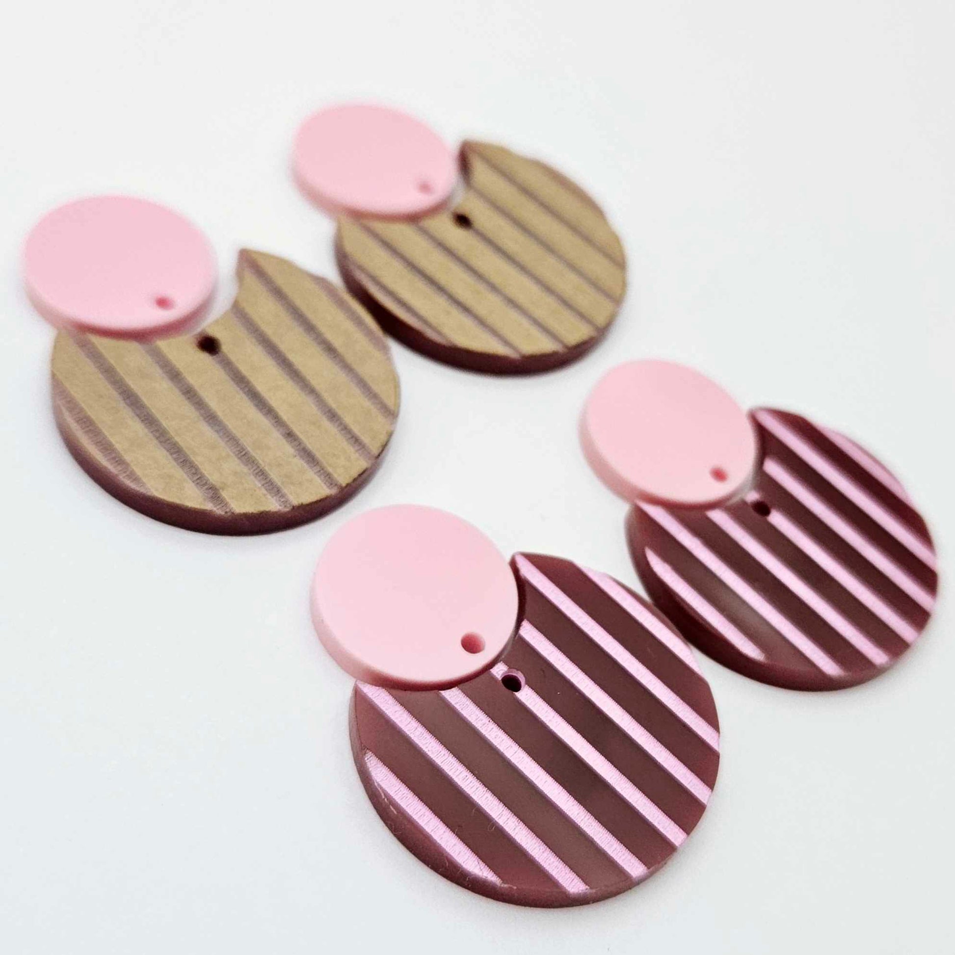 Nested circle dangle blanks showing one pair paint filled light pink and peeled, with another pair unpainted and with protective film on