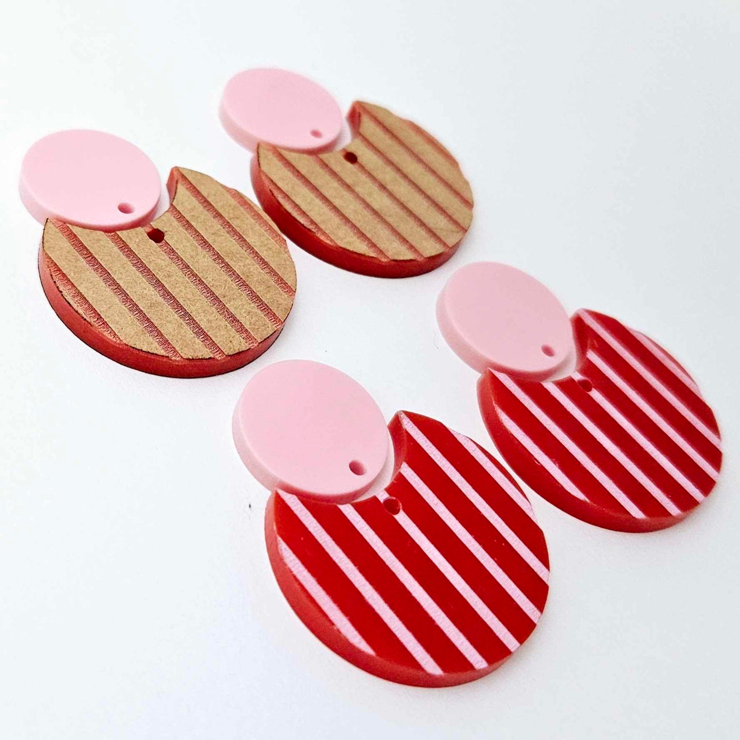 Nested circle dangle blanks showing one pair paint filled light pink and peeled, with another pair unpainted and with protective film on