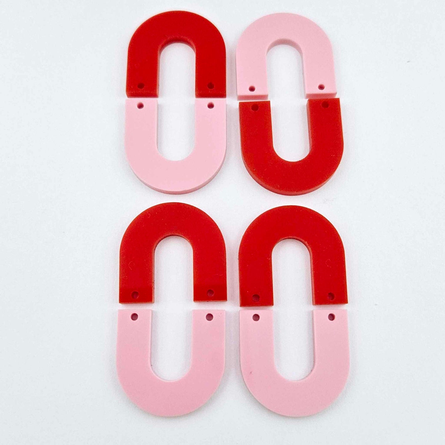 Layered U dangle blanks in pastel pink and red acrylic, two pairs shown unassembled laying flat with matching U-shaped pieces