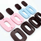 Two pairs of layered rectangle dangle blanks in chocolate brown and pastel pink/blue acrylic, unassembled pieces laid flat showing three-piece design