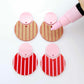 Nested circle dangle blanks showing one pair paint filled light pink and peeled, with another pair unpainted and with protective film on, pictured with a pink Posca paint pen