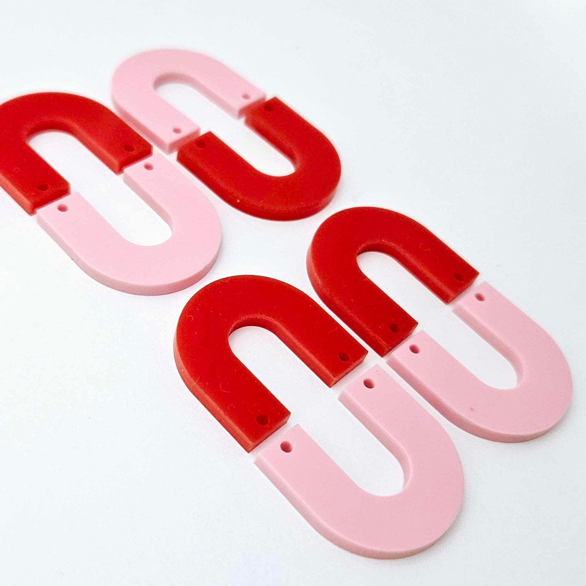 Layered U dangle blanks in pastel pink and red acrylic, two pairs shown unassembled laying flat with matching U-shaped pieces