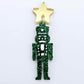 Assembled 40mm nutcracker Christmas dangle earrings in green glitter acrylic with engraved detail paint filled white