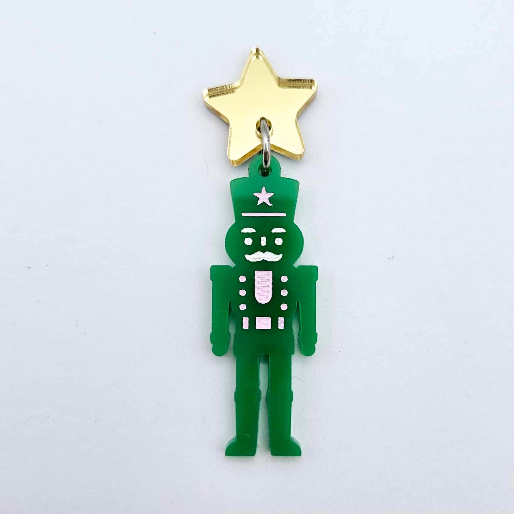 Assembled 40mm nutcracker Christmas dangle earrings in green acrylic with engraved detail paint filled with pink and white