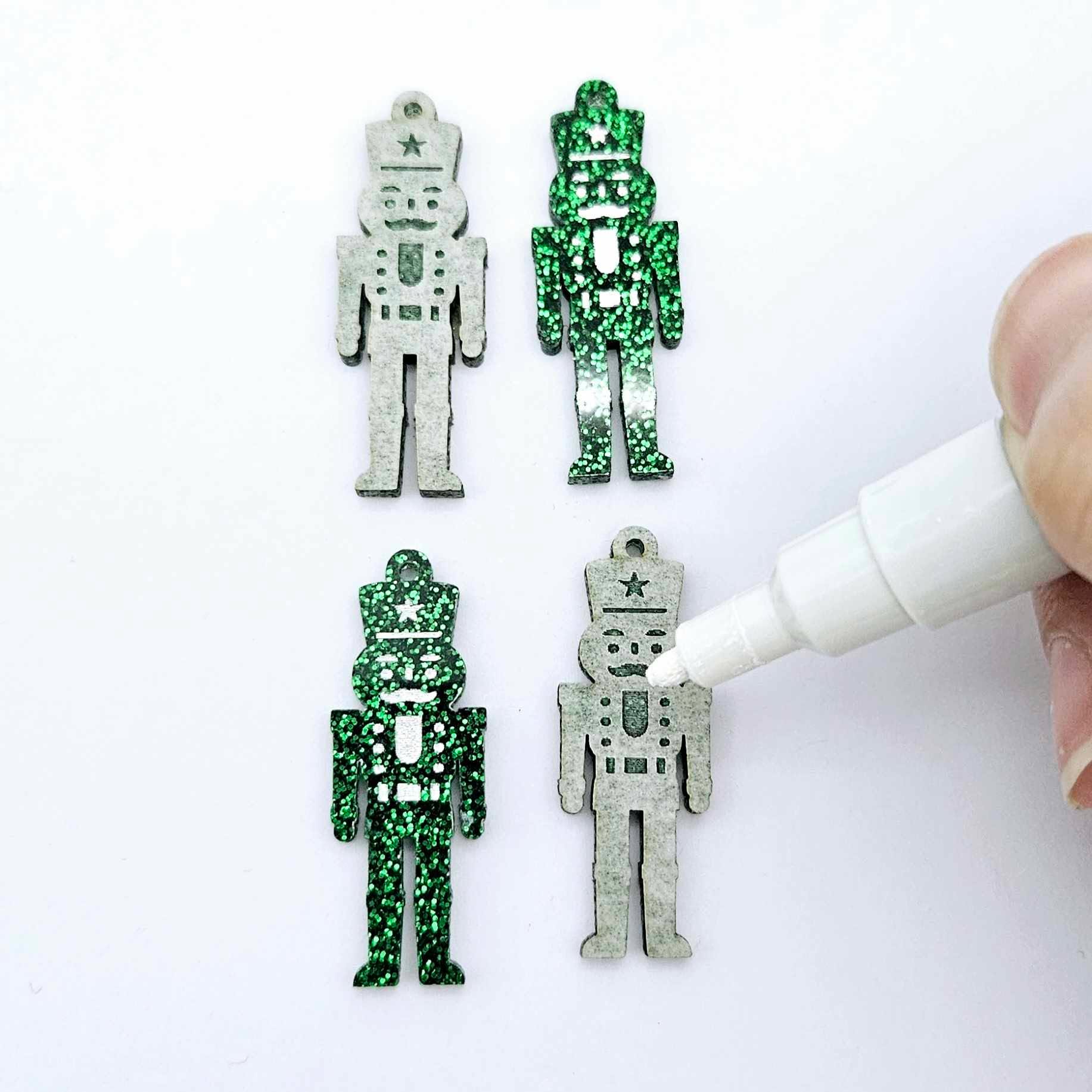 A pair of 40mm nutcracker Christmas dangle earring blanks in green glitter acrylic with engraved detail paint filled white with a paint not painted