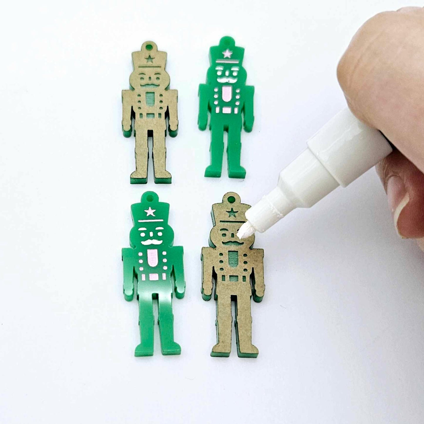 40mm nutcracker Christmas dangle blanks with engraved paint-fill details shown in  green acrylic with white posca paint pen painting a piece