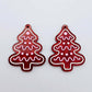 One pair of deep red marble cookie Christmas tree dangle blanks with engraved icing details paint filled in light pink and white, shown laying flat