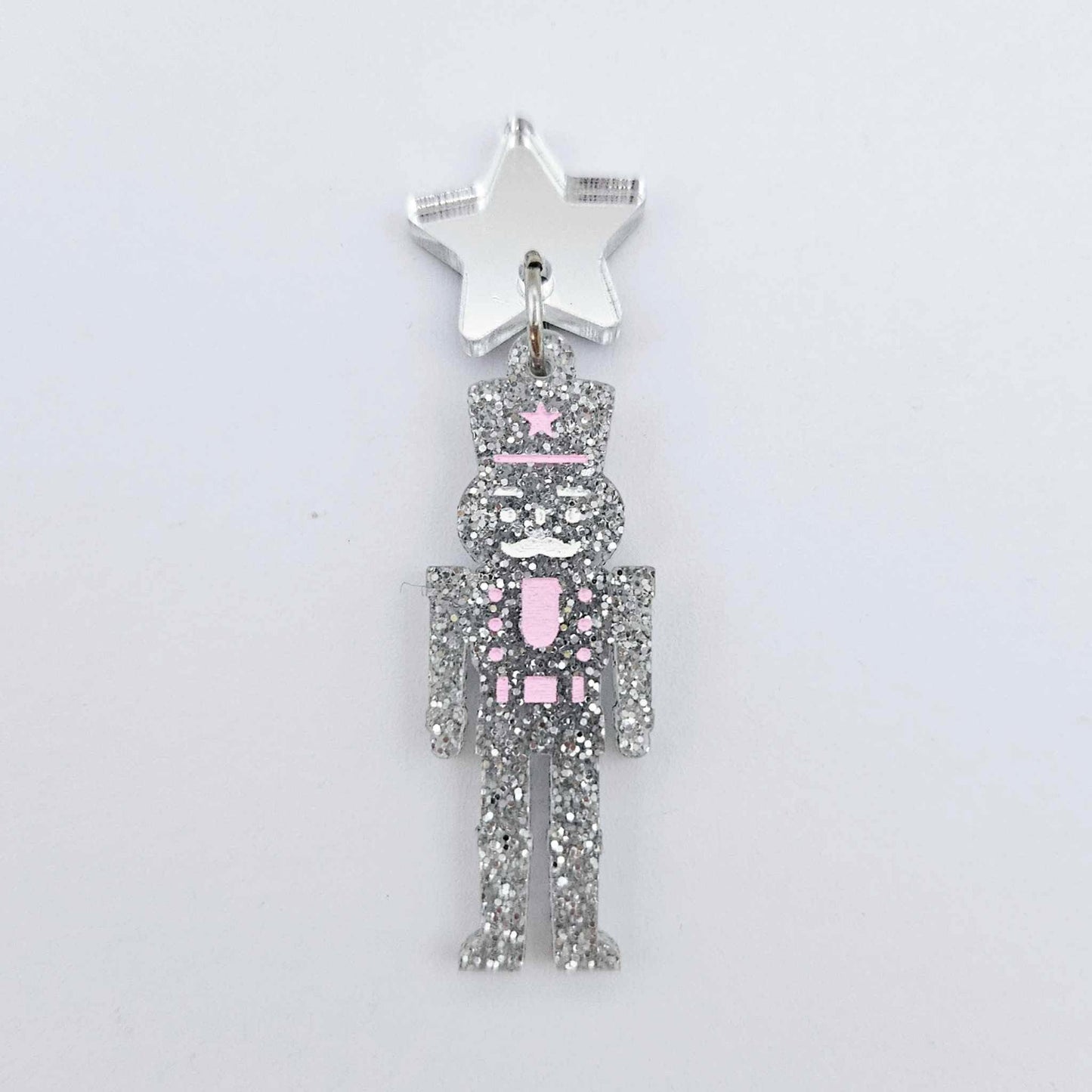 Assembled 40mm nutcracker Christmas dangle earrings in silver glitter acrylic with engraved detail paint filled white and pink