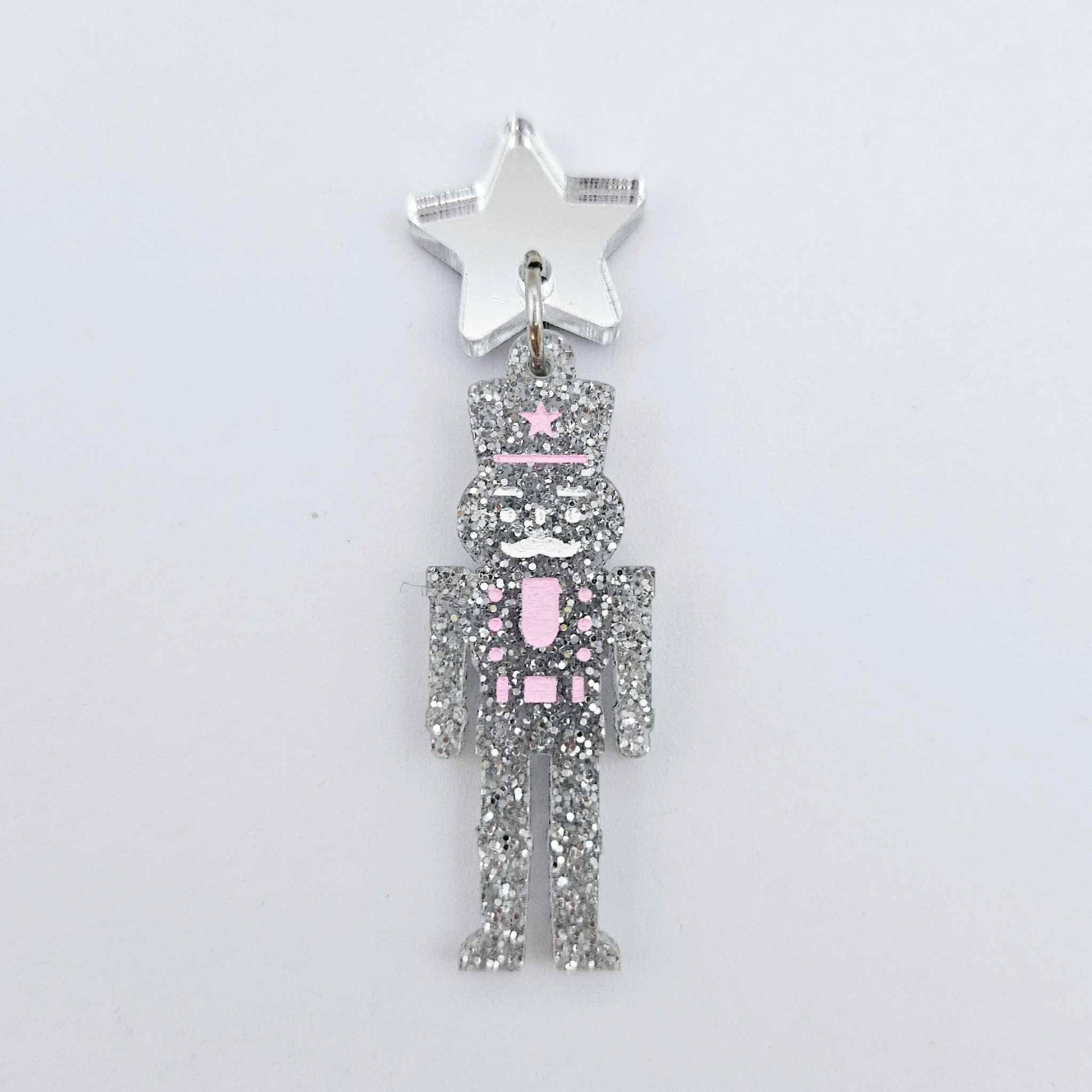 Assembled 40mm nutcracker Christmas dangle earrings in silver glitter acrylic with engraved detail paint filled white and pink