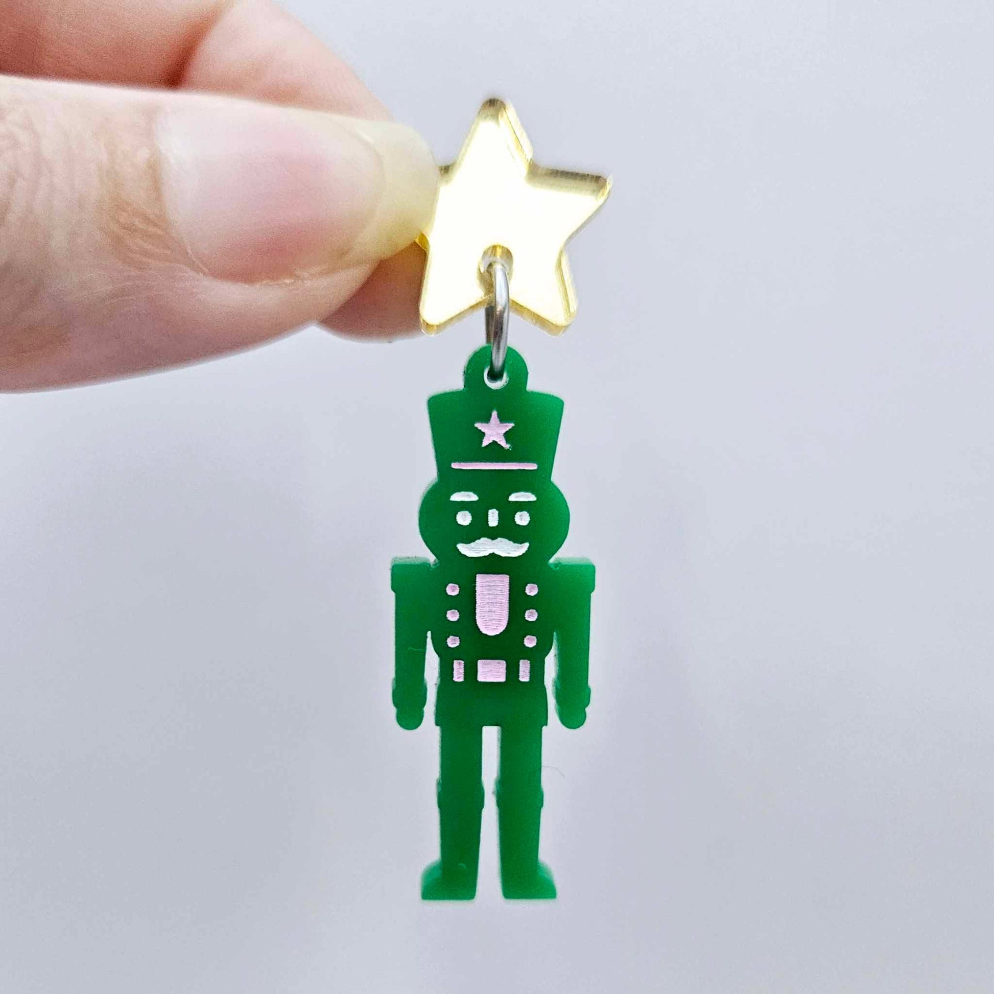 Assembled 40mm nutcracker Christmas dangle earrings in green acrylic with engraved detail paint filled with pink and white