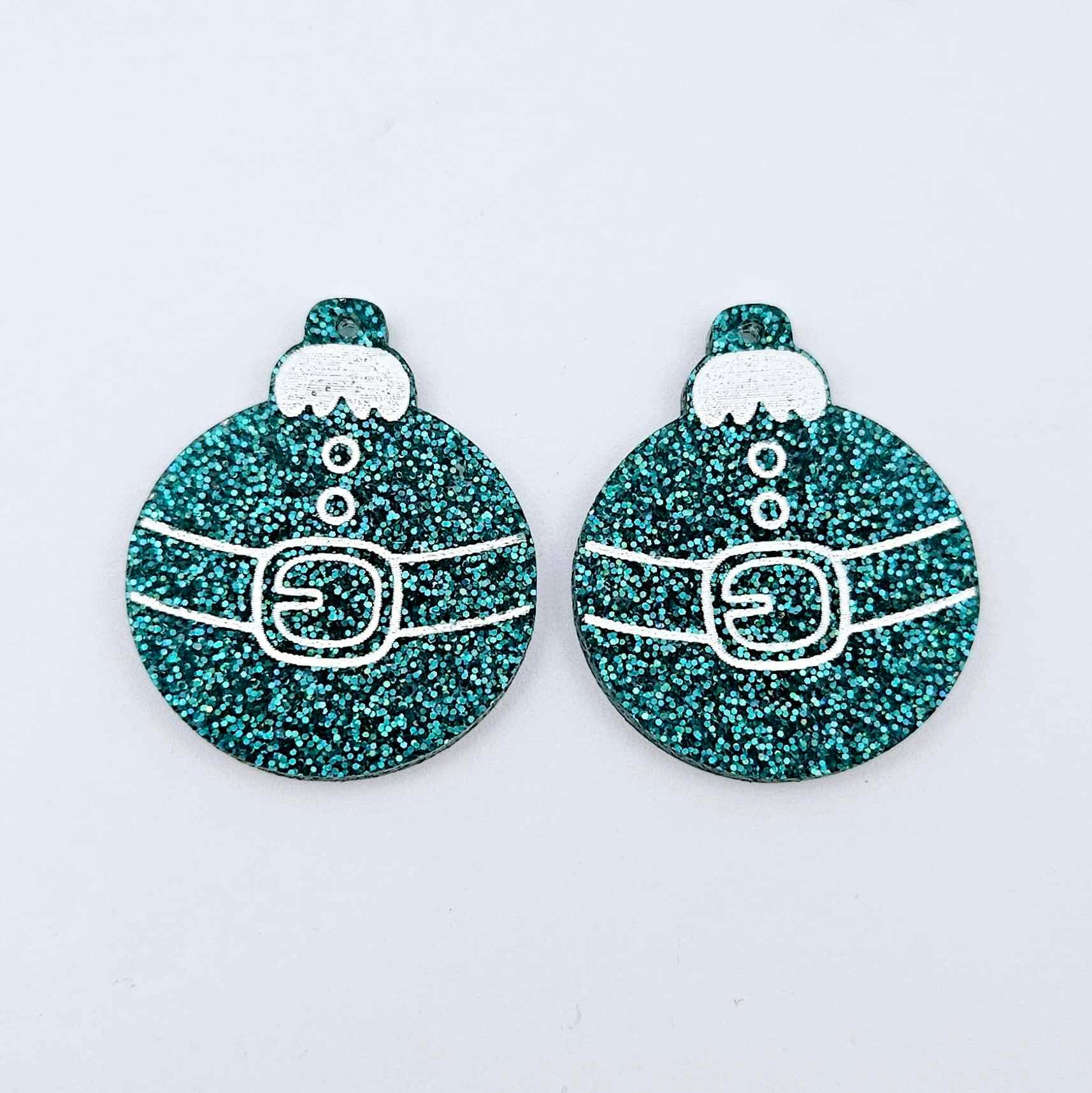 One pair of teal glitter Santa bauble dangle blanks with engraved Santa belt and button details paint filled white, shown laying flat