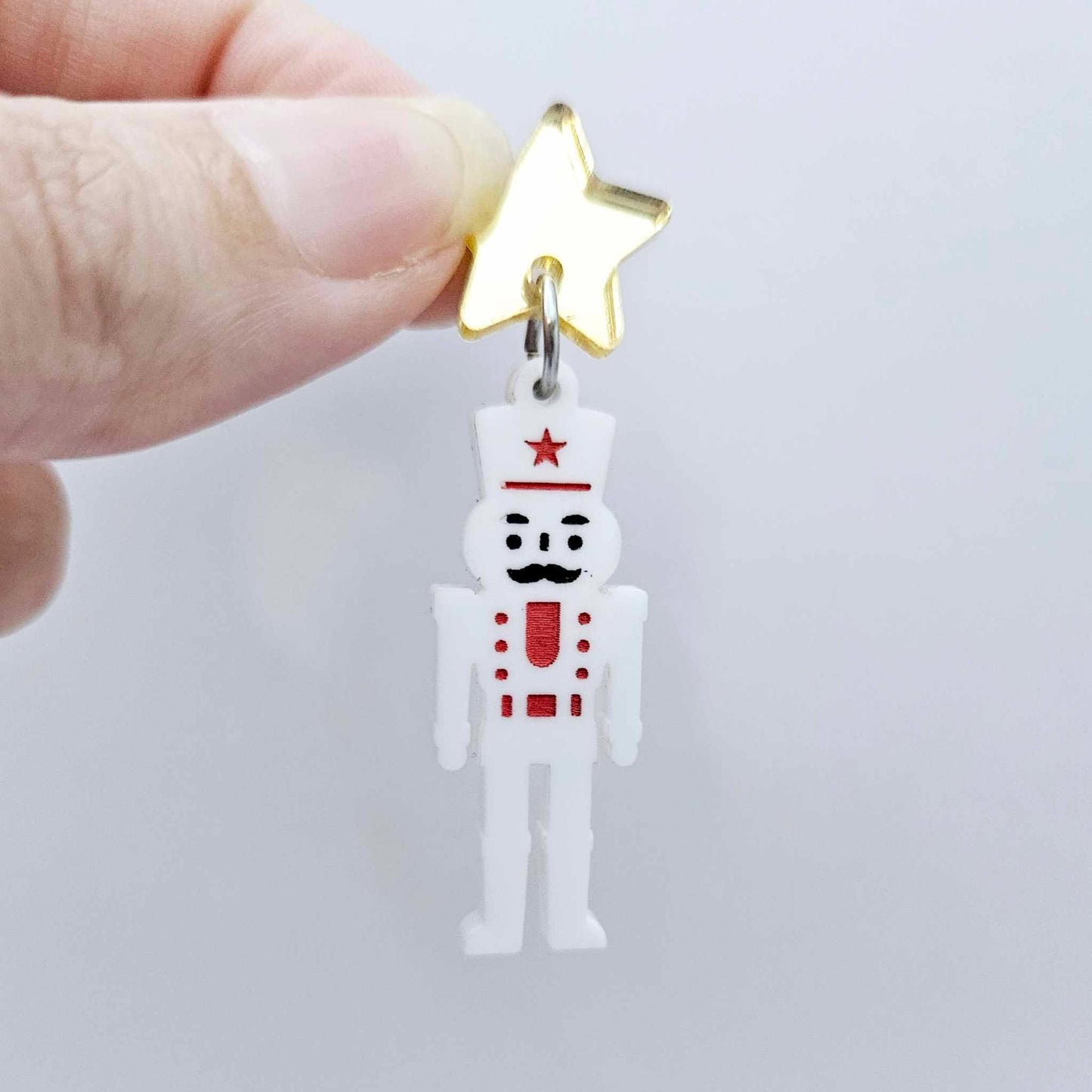 Assembled 40mm nutcracker Christmas dangle earrings in white acrylic with engraved detail paint filled with red and black