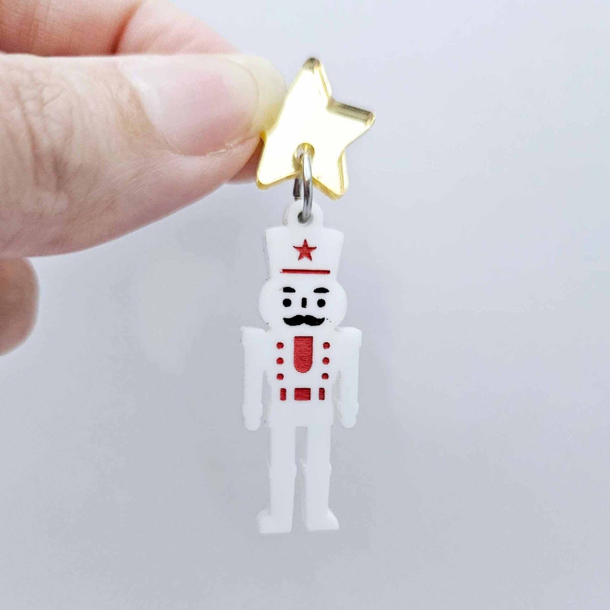 Assembled 40mm nutcracker Christmas dangle earrings in white acrylic with engraved detail paint filled with red and black