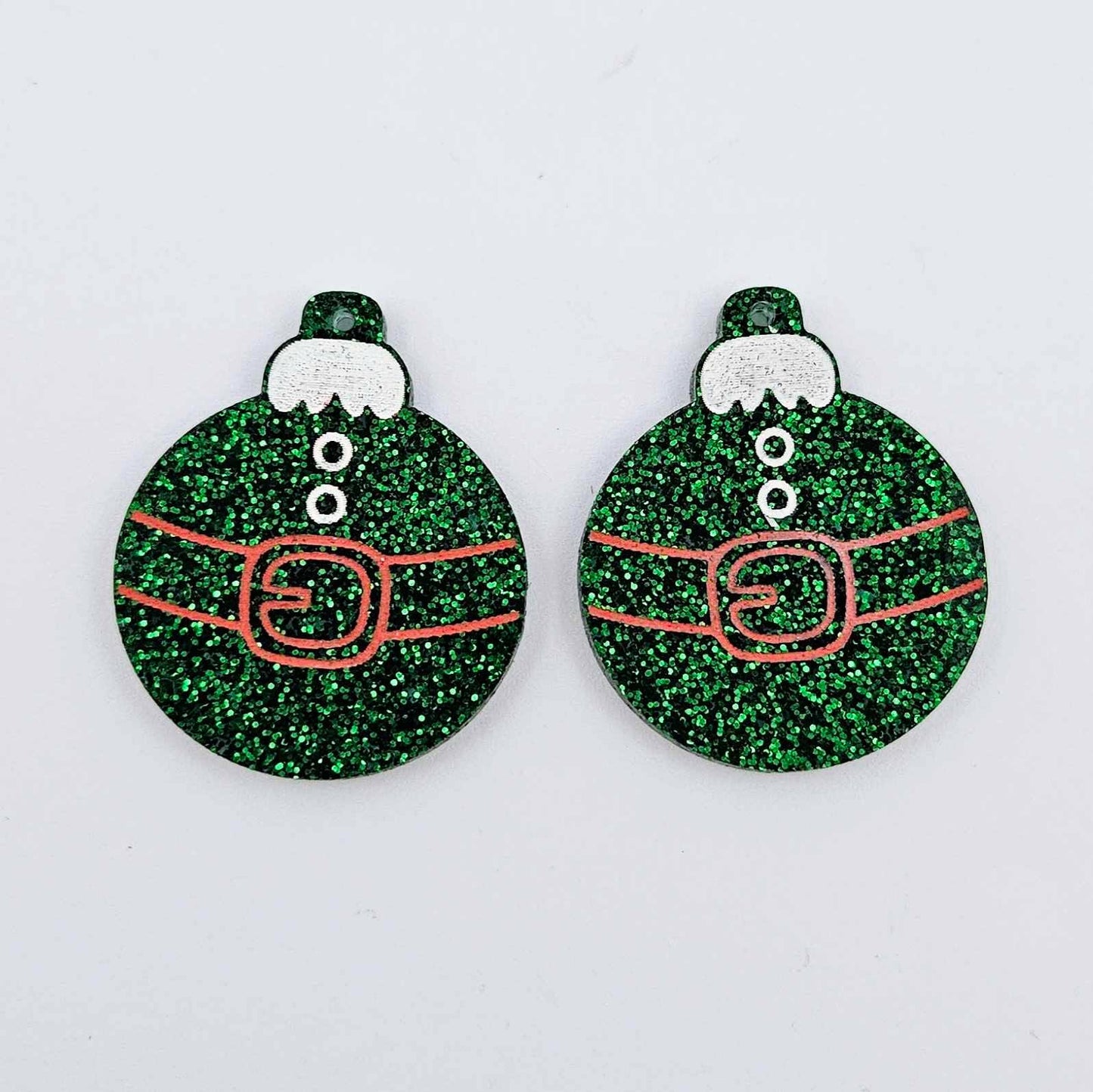 One pair of green glitter Santa bauble dangle blanks with engraved Santa belt and button details paint filled red and white, shown laying flat