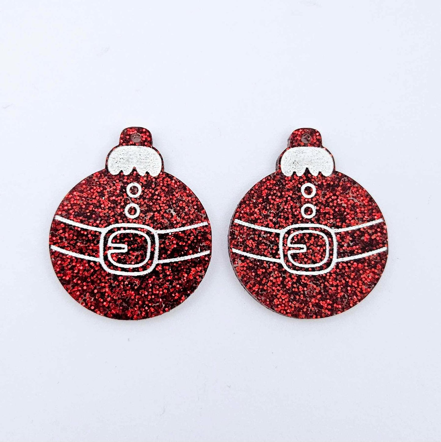 One pair of red glitter Santa bauble dangle blanks with engraved Santa belt and button details paint filled white, shown laying flat